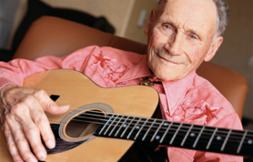 Image of a Masterpiece Retirement resident playing guitar